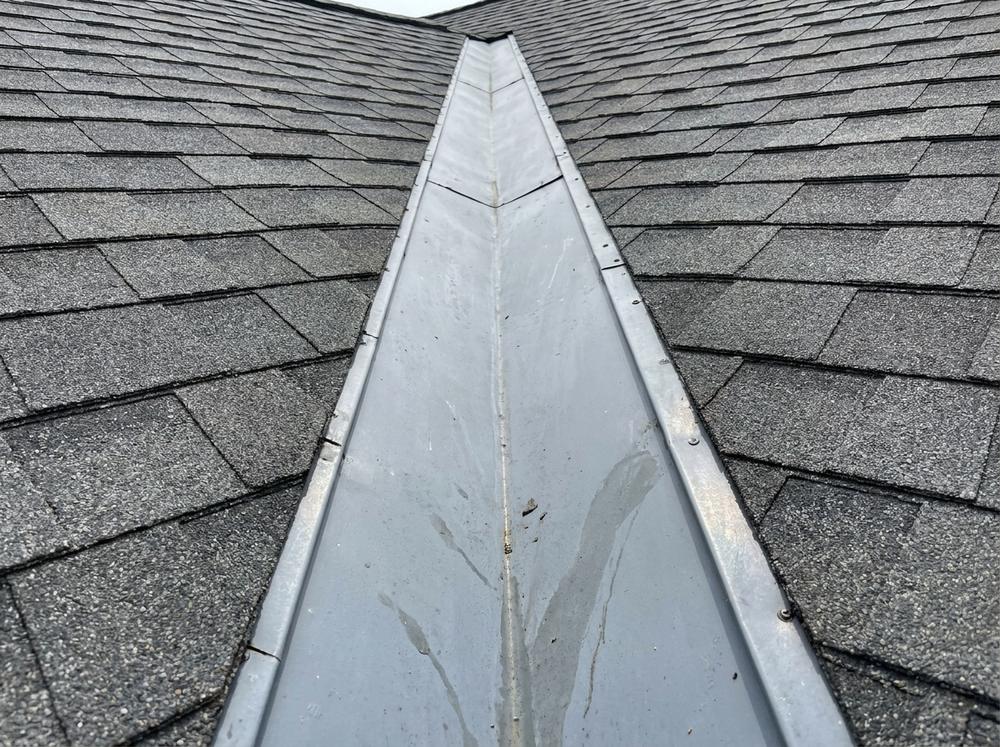 Open roof valley lined with metal, shingles cut back on both sides
