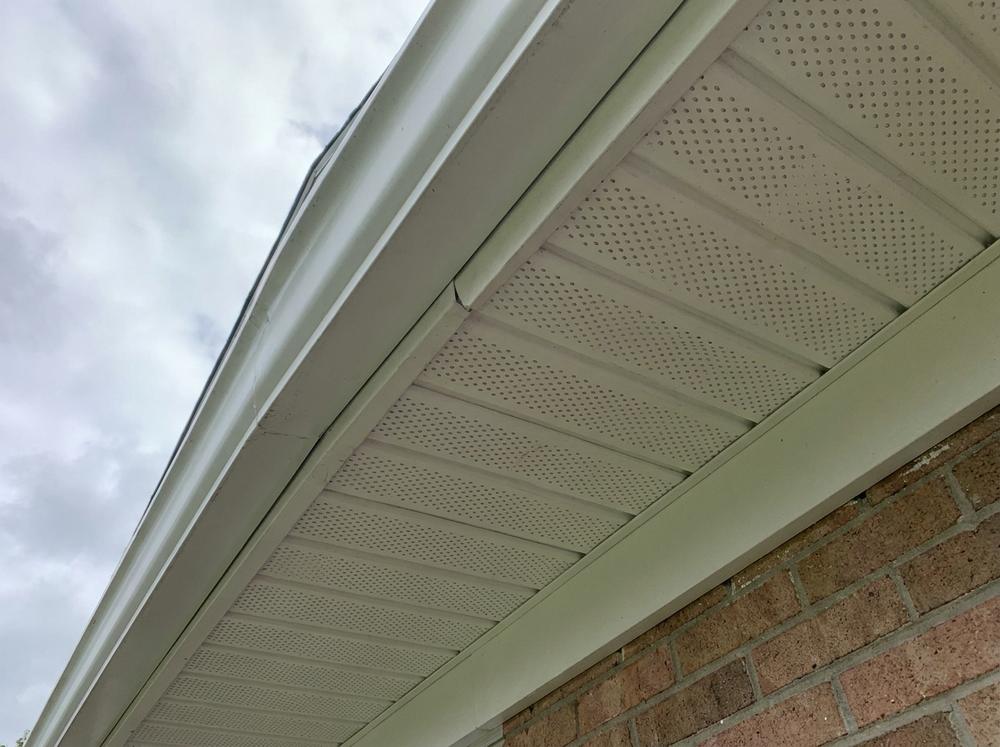 Perforated soffit panels under a roof eave overhang seen from below