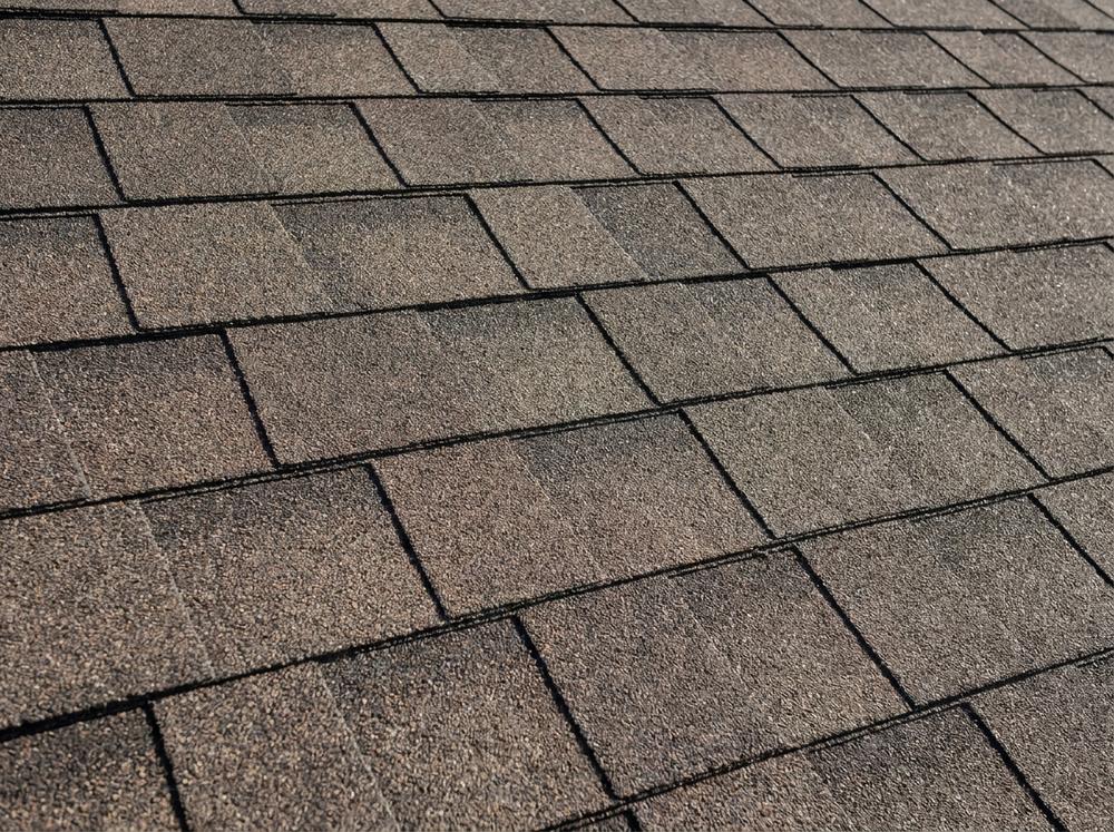 Close-up of a brown architectural laminated asphalt shingle roof showing shadow lines